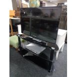 A Samsung 32" LCD TV with remote together with a Philips DVD player on three tier black glass stand