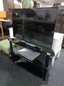 A Samsung 32" LCD TV with remote together with a Philips DVD player on three tier black glass stand