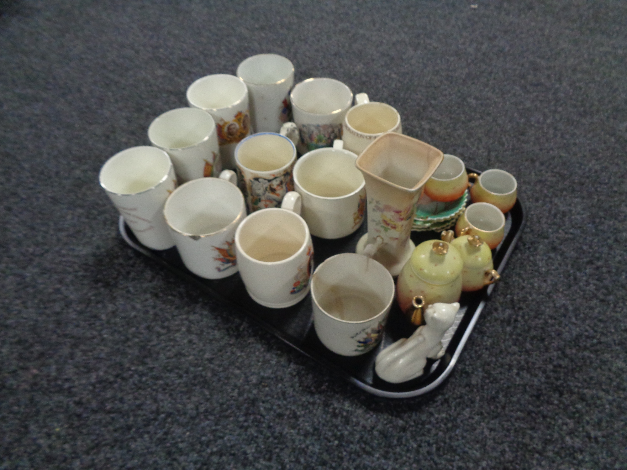 A tray of early 20th century and later commemorative mugs and beakers, Goss cat figure,