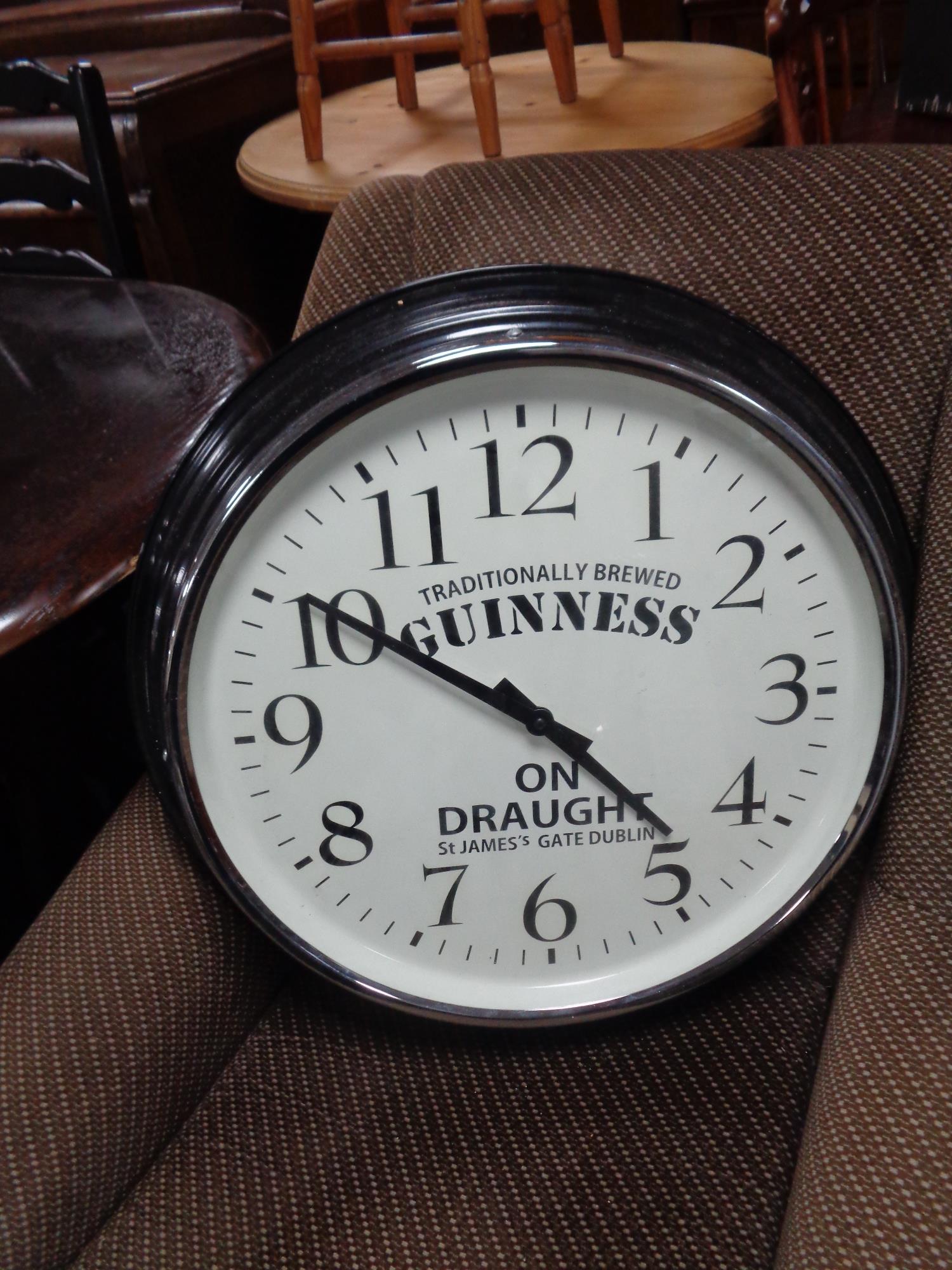 A circular wall clock bearing Guinness advertising