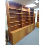 A four piece mid 20th century teak bookcase fitted double door cupboards beneath