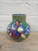 A W Moorcroft vase decorated with orchids on green ground, height 12.