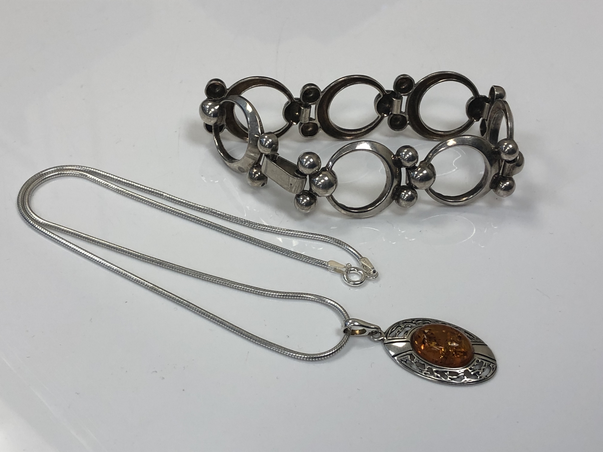 An abstract silver bracelet, together with a silver Baltic amber pendant on chain.