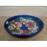A W Moorcroft shallow bowl decorated with orchids on blue ground,