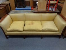 An antique mahogany framed low back settee upholstered in gold fabric, height 70 cm, width 222 cm,
