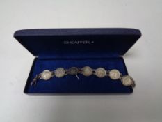 A silver bracelet with seven George V silver thurpenny pieces