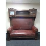 An early 20th century continental oak high-backed hall settee upholstered in a red fabric,