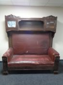 An early 20th century continental oak high-backed hall settee upholstered in a red fabric,