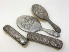 An Art Nouveau silver back hand mirror and three silver backed brushes (4)