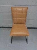 A contemporary brown leather dining chair on tubular legs