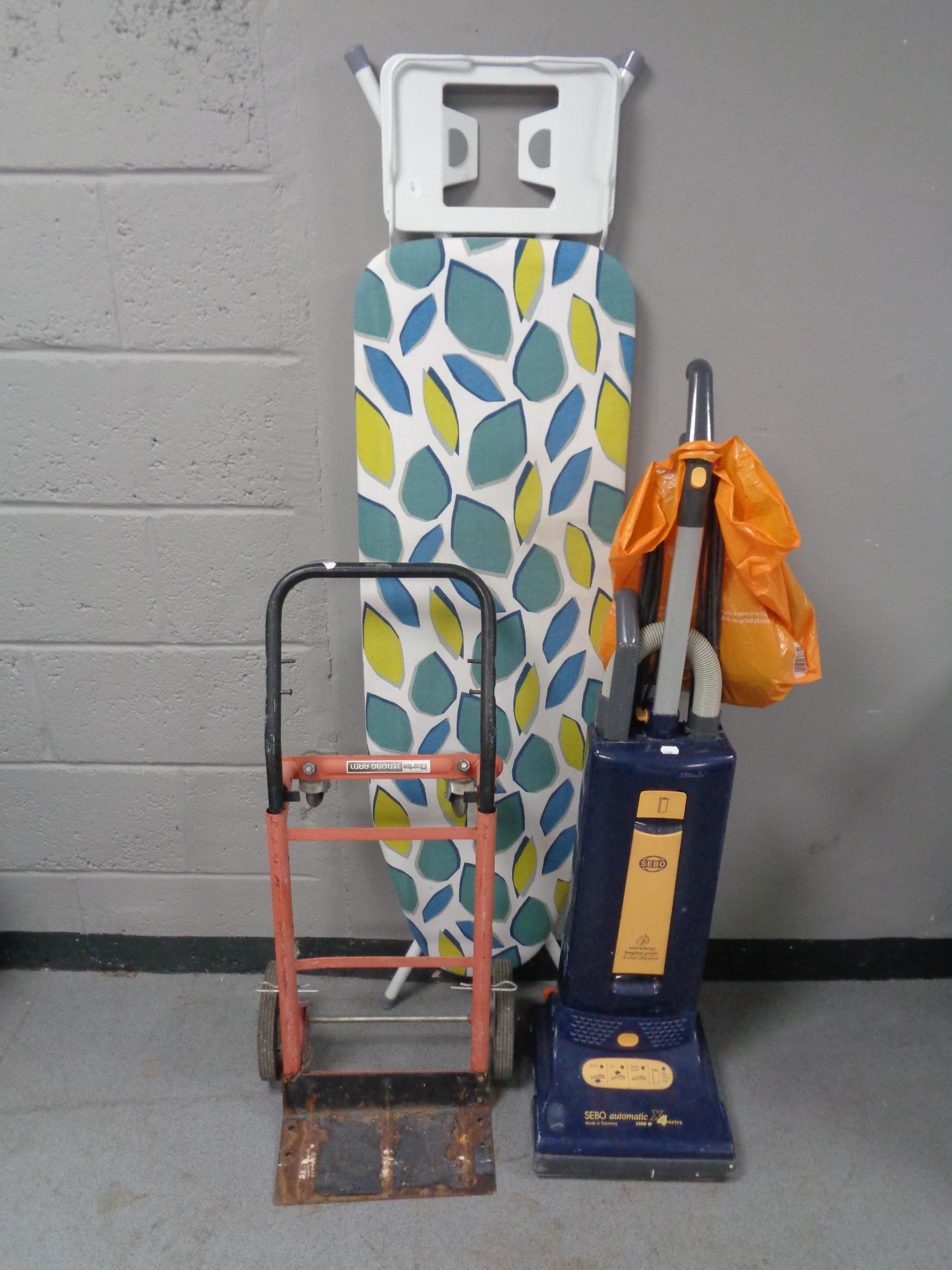 A Sebo automatic vacuum together with a Clark Strongarm sack barrow and ironing board