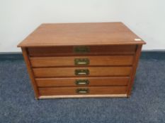 A 20th century hardwood desk top five drawer chest with brass drop handles