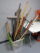 A plastic box of garden tools and brushes