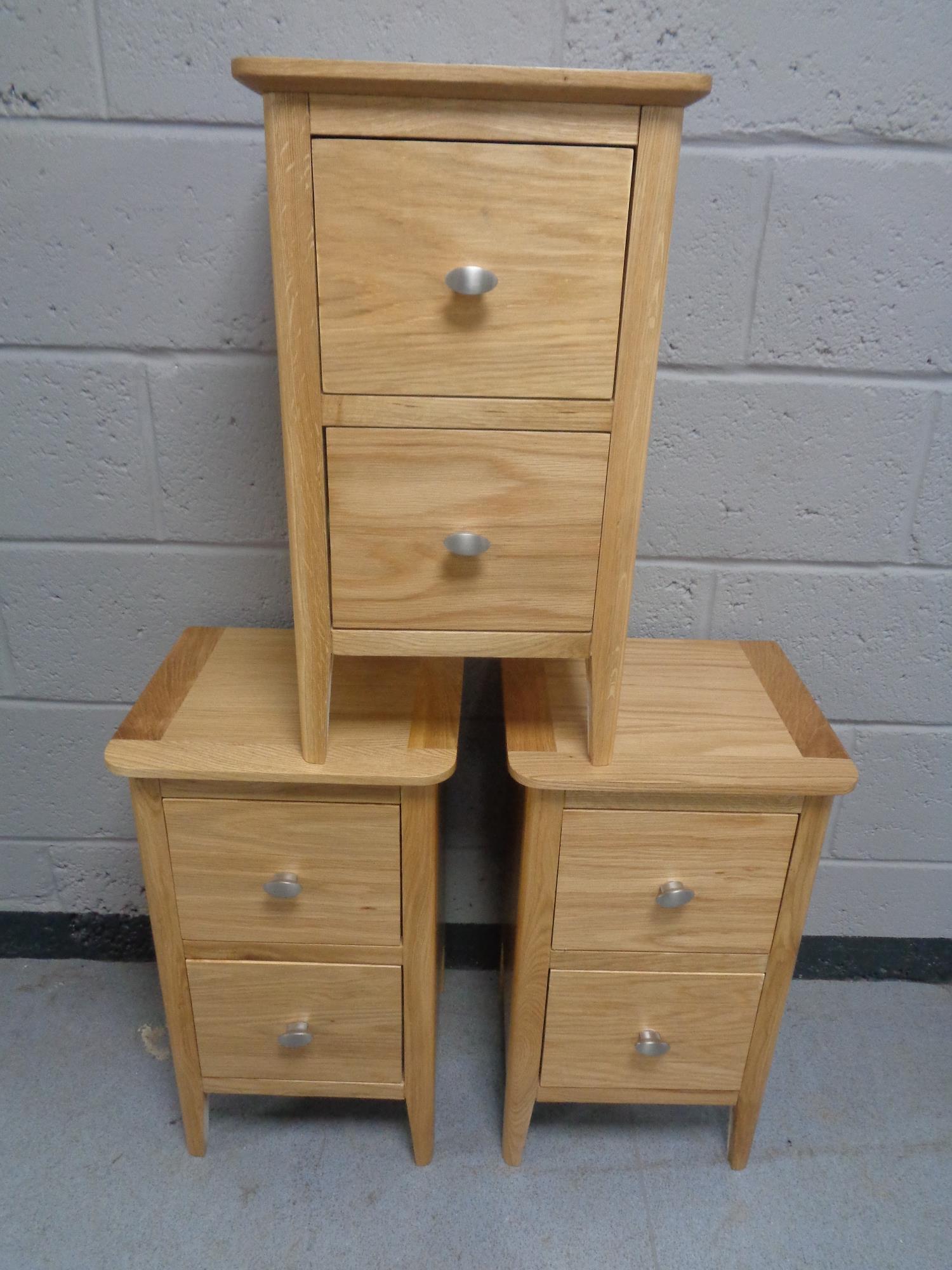 A set of three contemporary two drawer bedside stands in an oak finish