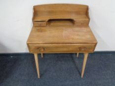 An Ercol solid elm and beech single drawer writing table with back shelf fitted two drawers,