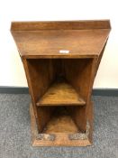 A solid oak Arts and Crafts bookcase with carved plinth and angular shelves.