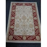 A machine made woolen rug of floral design on cream ground