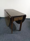 An antique oak drop leaf table fitted a drawer