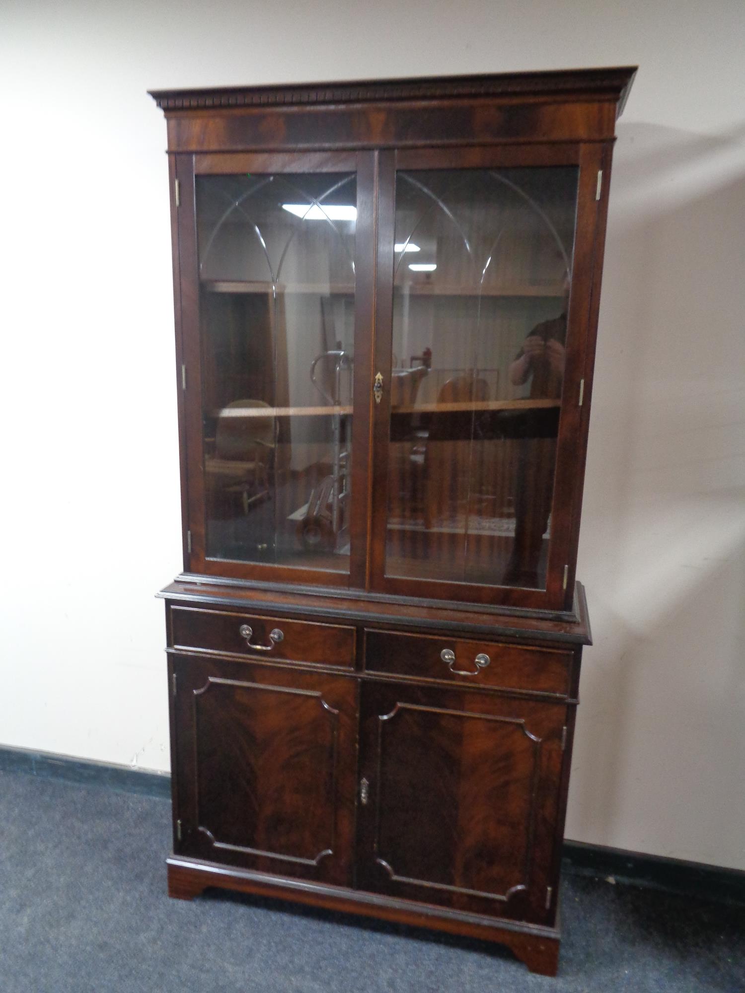 A reproduction mahogany bookcase with cupboards and drawers beneath
