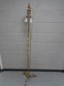 An antique brass standard lamp on three way pedestal