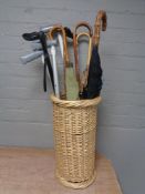 A wicker stick stand containing 20th century and later parasols and walking sticks