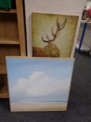 A framed print depicting figures on a beach together with a wall canvas of a stag