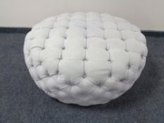 A circular oversized footstool in button fabric