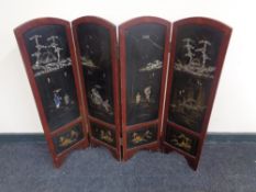 An early 20th century four fold lacquered screen with mother of pearl decoration depicting Geisha,