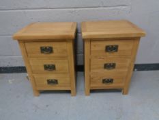 A pair of contemporary oak three drawer bedside chest with metal drop handles