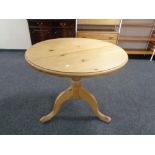 A circular pine kitchen table on pedestal