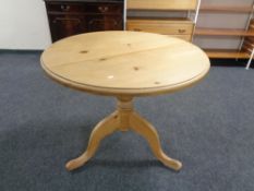 A circular pine kitchen table on pedestal