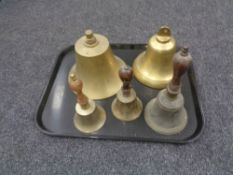 A tray containing two brass ship's style bells together with three further brass wooden handled