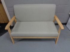 A contemporary pine framed two seater settee