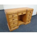 An antique pine kneehole desk fitted nine drawers