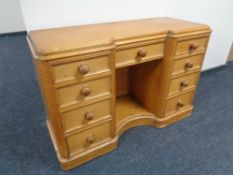 An antique pine kneehole desk fitted nine drawers