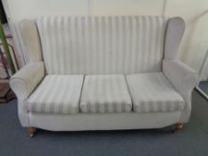 A three seater wing backed settee in striped fabric