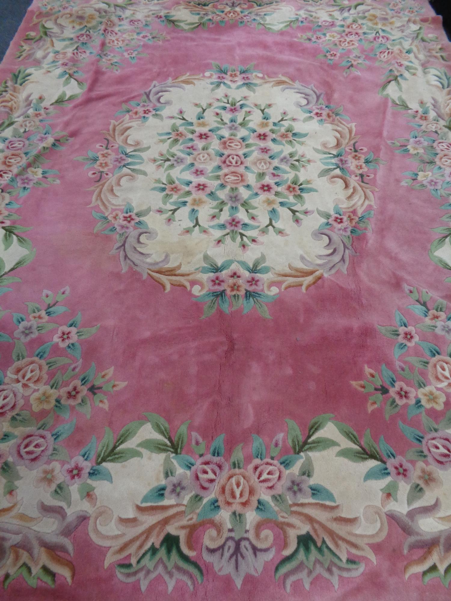 A large pink floral fringed Chinese carpet,