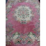 A large pink floral fringed Chinese carpet,