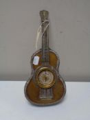 An ornate white metal table barometer in the form of a guitar