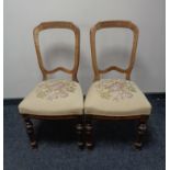 A pair of antique dining chairs with a floral tapestry upholstered seat