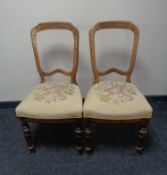 A pair of antique dining chairs with a floral tapestry upholstered seat