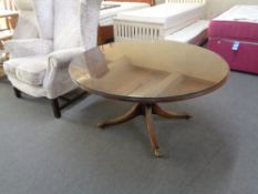 An inlaid mahogany circular pedestal coffee table on brass castors with plate glass top