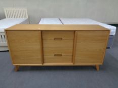 A contemporary oak sliding door sideboard fitted with four central drawers