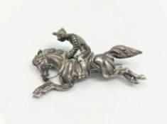 An antique silver brooch in the form of a jockey on horseback