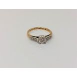 An antique 18ct gold diamond solitaire ring with diamond set shoulders,