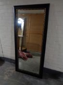 A 5' by 2' mirror in a black and gilt frame
