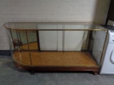 An Edwardian brass framed shaped shop display cabinet (glass a/f),