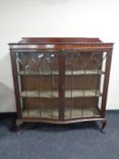 An Edwardian mahogany serpentine fronted double door display cabinet on claw and ball feet