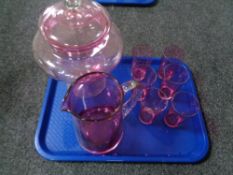 A tray of cranberry glass ware, water jug, six beakers,