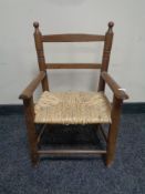 An early twentieth century stained beech framed rush seated child's armchair